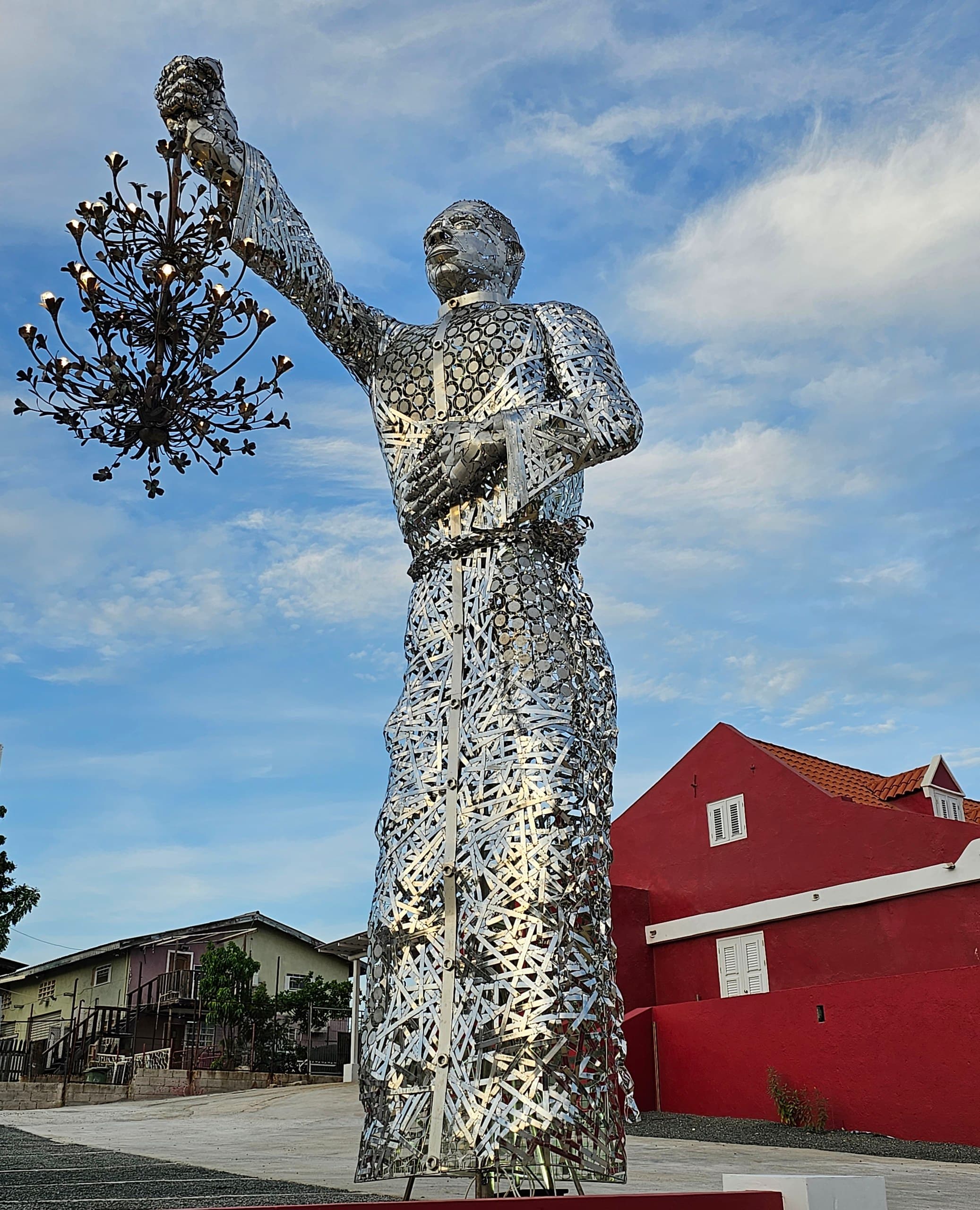 Giovanni Abath's 7.1-meter Light Bearer sculpture in front of the red gallery at Landhuis Morgenster, Curaçao